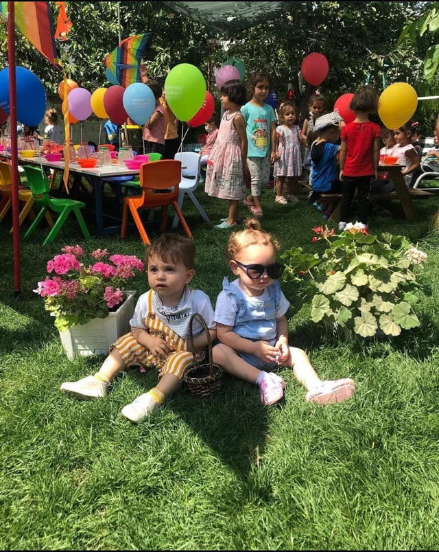 Balonlarla süslenmiş bahçede piknik yapan çocuklar