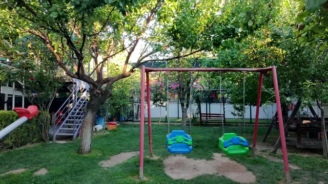 Ağaçların gölgesinde renkli salıncaklar