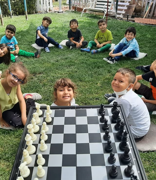 Bahçede satranç tahtası başında gülümseyen çocuklar